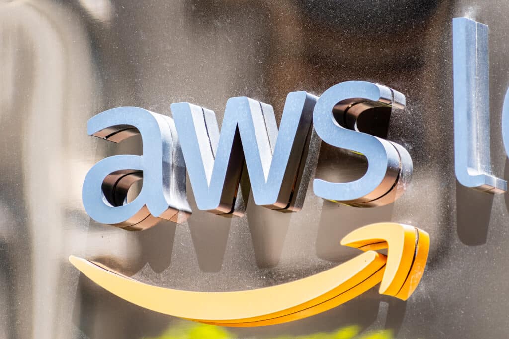 Close-up of the metallic aws logo with Amazon’s signature yellow arrow underneath, displayed on a reflective surface.